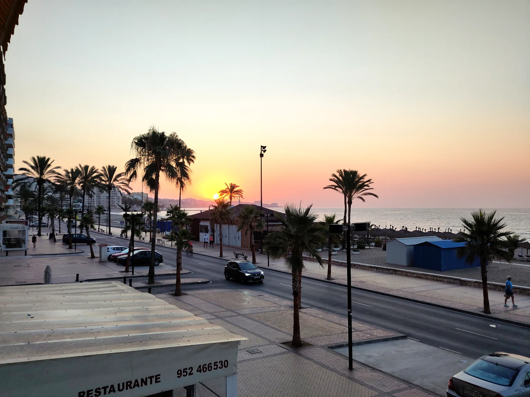 Solnedgang over promenade og palmer ved den spanske kyst