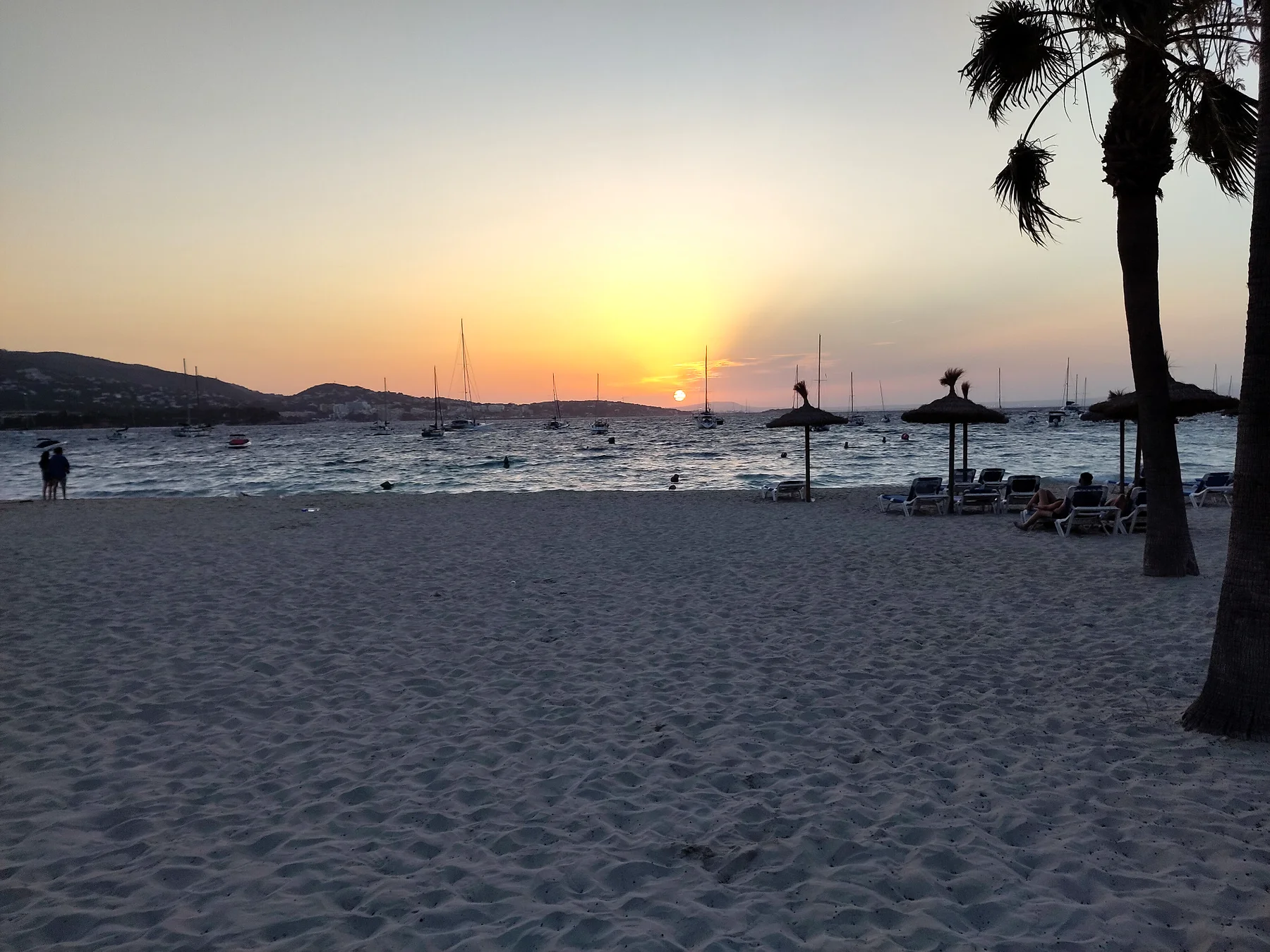 Solnedgang på stranden med både og stille aftenstemning